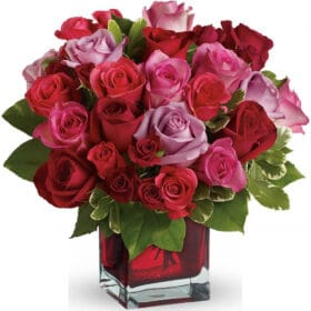 Arreglo de rosas rojas y rosadas en florero en forma de cubo rojo